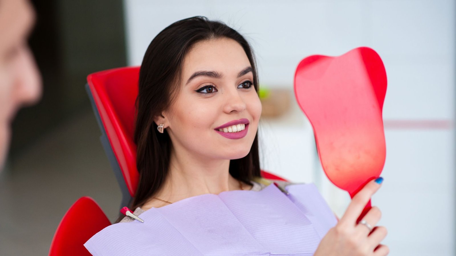 Patient smiling at her reflection in a hand mirror